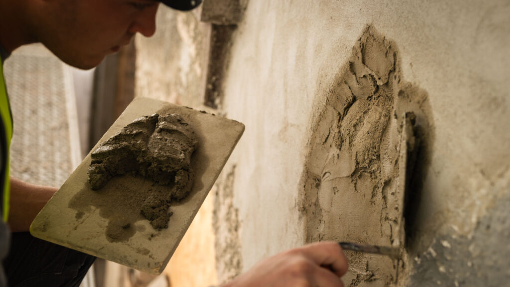 Nahaufnahme eines Mitarbeiters von Krieg Bausanierung beim Spachteln